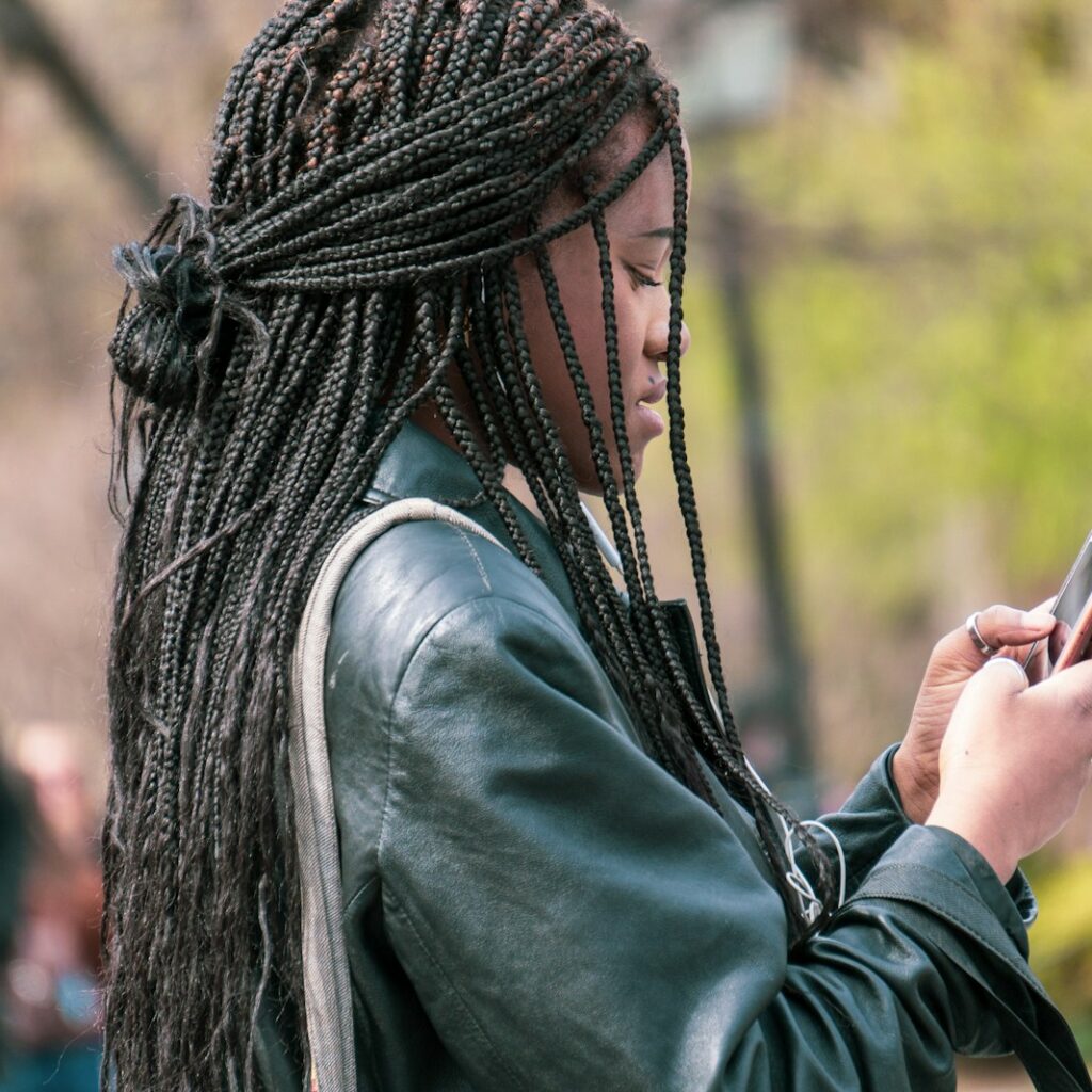 a woman with dreadlocks looking at her cell phone